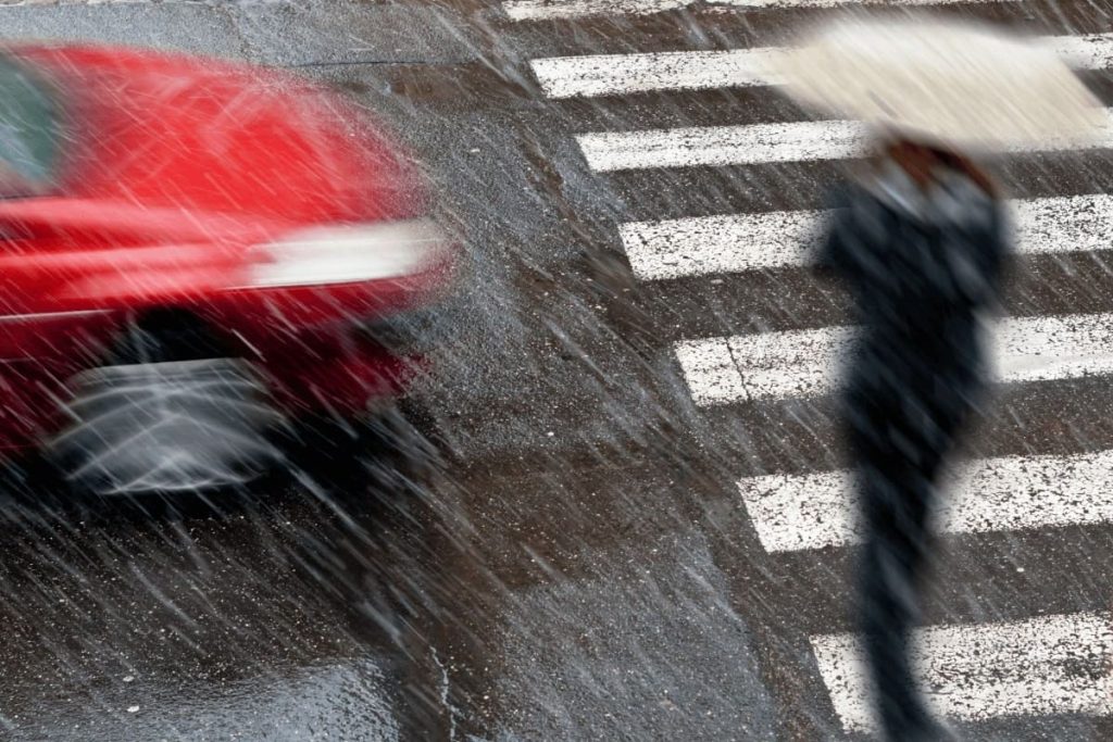 Pedestrian walking across the crosswalk with an oncoming car. Pedestrian accident claims.